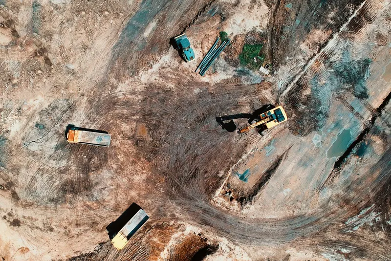 Aerial view of dump trucks and an excavator working a dirt site